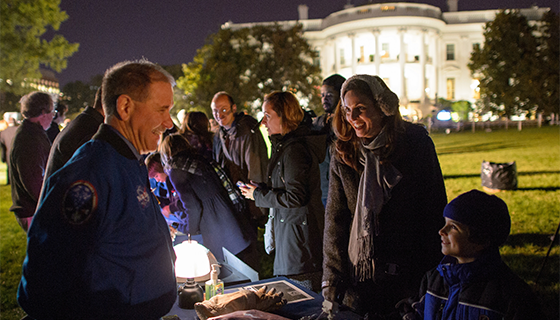 Former astronaut John Grunsfeld shows a spacesuit glove to a student on the White House Lawn during White House Astronomy Night