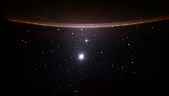 Earth's Moon, Venus and Jupiter line up below the horizon of Earth in this photo taken from the space station