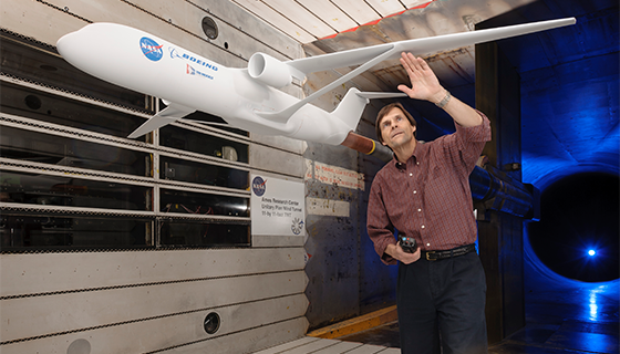 A man prepares an airplane model for testing in a wind tunnel