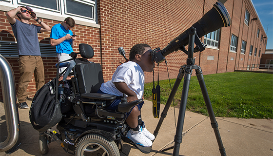 Outside his school building, a student peers through a telescope during the Mercury transit