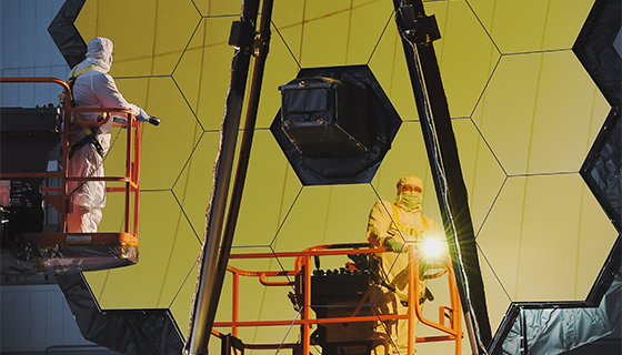 An engineer shines a flashlight at the mirrors of the James Webb Space Telescope