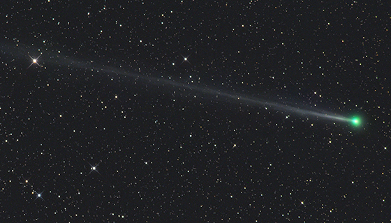 A bright comet with a greenish hue and a long tail