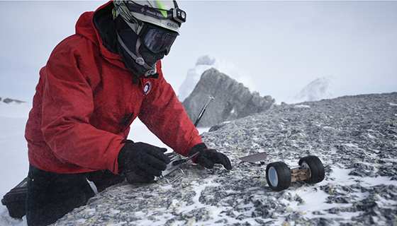 A scientist controls a small robotic rover in snowy Antarctica