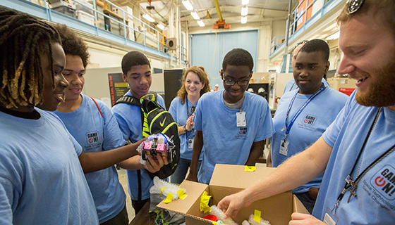 Students inspecting objects inside a cardboard box