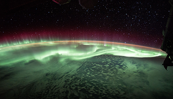 Brilliant green and pink aurora dance above Earth in this view from the space station