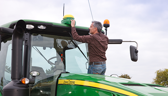A man adjusts an antenna on top of a large tractor