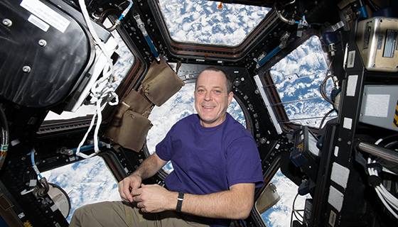 Ricky Arnold floats in front of the many windows of the space station cupola