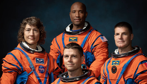 NASA astronauts Reid Wiseman, Christina Koch, and Victor Glover pose with Canadian astronaut Jeremy Hansen, all wearing orange spacesuits