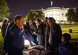 Former astronaut John Grunsfeld shows a spacesuit glove to a student on the White House Lawn during White House Astronomy Night