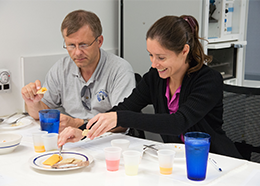 Two astronauts try crackers with cheese spread