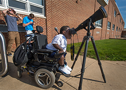 Outside his school building, a student peers through a telescope during the Mercury transit