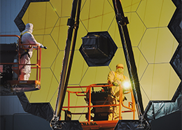 An engineer shines a flashlight at the mirrors of the James Webb Space Telescope