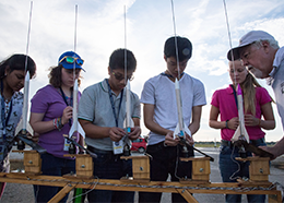 Five students place model rockets on a launch pad