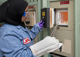 Sabah Bux uses a pair of tongs to place an object into a furnace