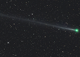 A bright comet with a greenish hue and a long tail