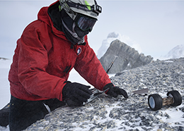 A scientist controls a small robotic rover in snowy Antarctica