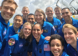 Seven men and five women wearing blue flight suits pose for a picture