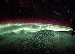 Brilliant green and pink aurora dance above Earth in this view from the space station