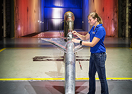 A female engineer and a silver airplane model inside a wind tunnel