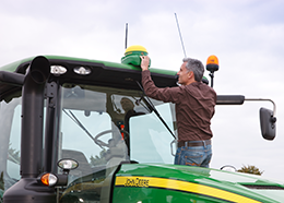 A man adjusts an antenna on top of a large tractor