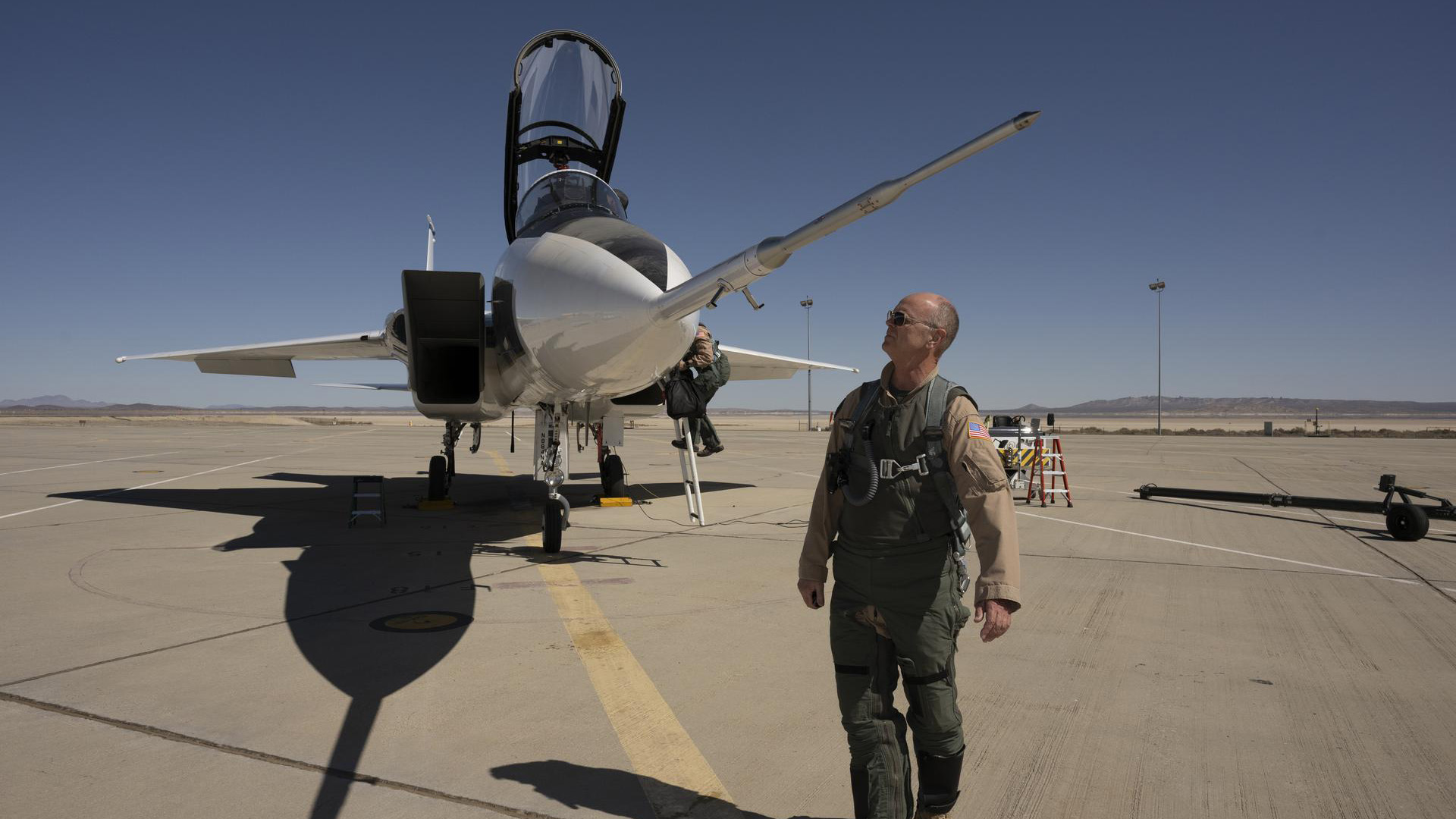 NASA test pilot David Nils Larson walks near the long, pointy probe sticking out from the nose of an F-15D jet airplane.