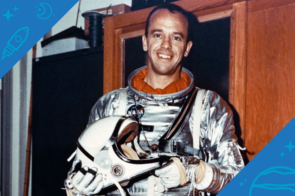 Astronaut Alan Shepard smiles while wearing an all-silver pressure suit for the Mercury mission. He holds a white helmet in his hands.