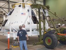Technicians at NASA Dryden connect one of two mobilizer units to the Orion flight test crew module transportation fixture in preparation for loading the module onto an Air Force C-17 cargo aircraft for transport to the White Sands Missile Range in New Mexico.