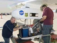 NASA Dryden's Ikhana ground crewmen Gus Carreno and James Smith load the thermal-infrared imaging scanner pallet into the Ikhana's underwing payload pod.