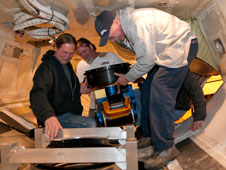 Dryden mechanic Larry Phillips (right), assisted by crew chief Pat Lloyd (left) and mechanic Donny Bailes (rear), mounts the Conical Scanning Millimeter-wave Imaging Radiometer, or CoSMIR, on a frame in the belly of NASA's DC-8 airborne science laboratory.