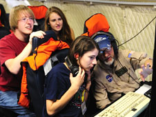Students watch intently as Dennis Gearhart from NASA Ames and UC-Santa Cruz details data from the MASTER remote sensing instrument on NASA's P-3B Earth sciences aircraft is displayed on a monitor in front of them during a research flight.