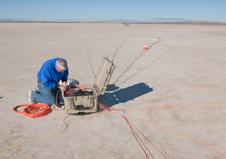 Like being in the center of a giant orange spider web, a FaINT project researcher connects microphone wiring for a spiral array designed to collect sonic boom data for the project.