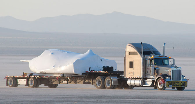 With its wings and tail structure removed and shrouded in protective plastic wrap, Sierra Nevada Corporation's Dream Chaser engineering test vehicle is hauled across the bed of Rogers Dry Lake at Edwards Air Force Base, Calif., to NASA's Dryden Flight Research Center May 15, 2013.