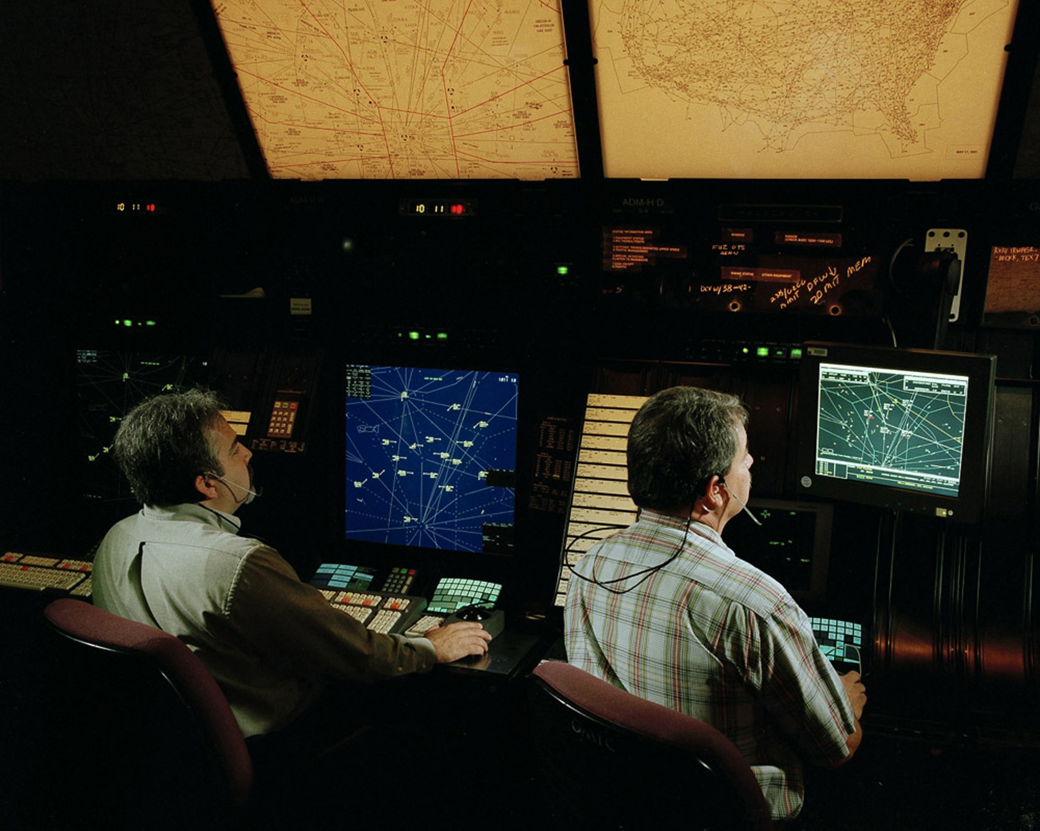 Two air traffic controllers looking at their monitors.
