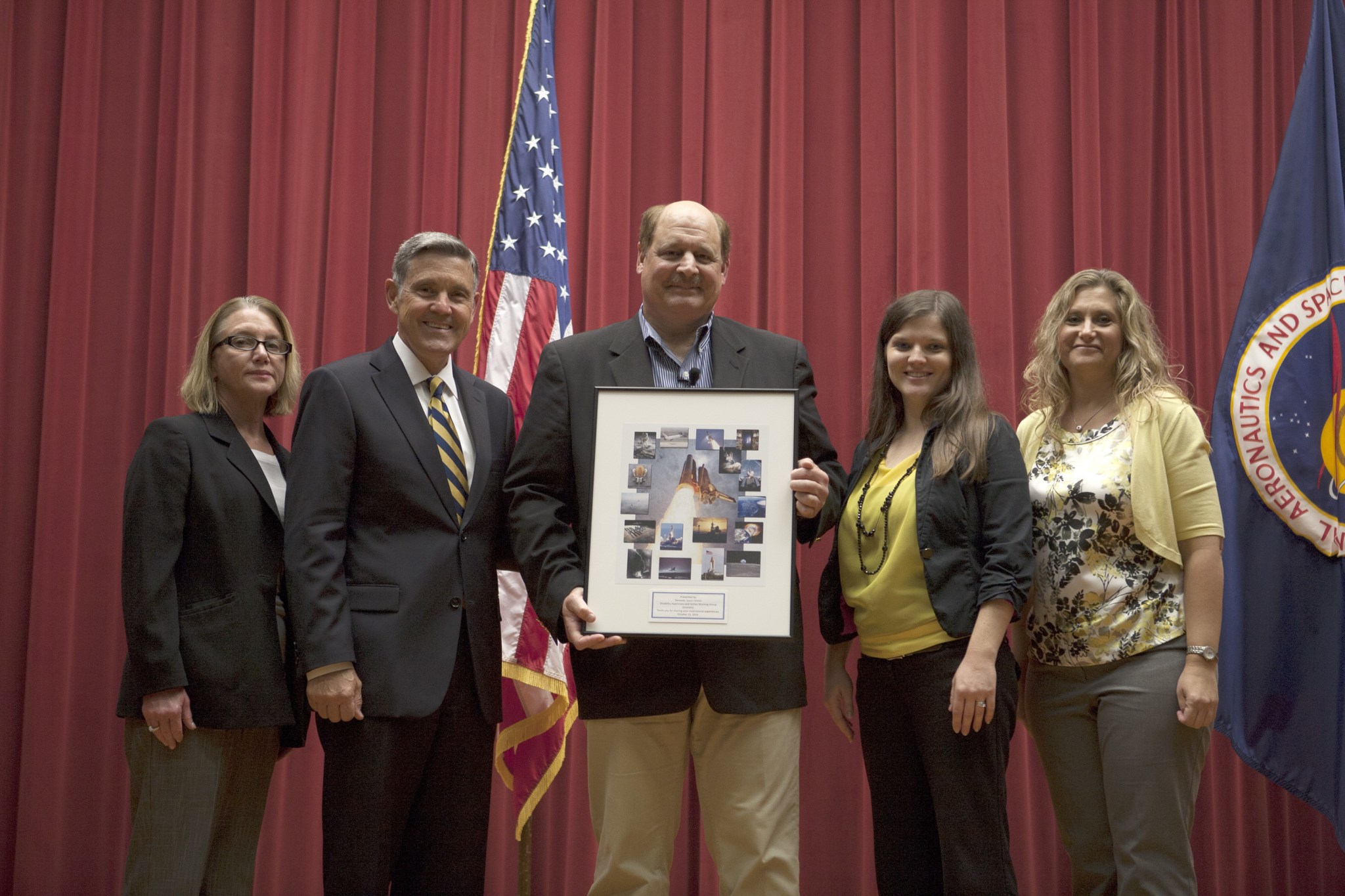 Michael Kersjes, center, author and former special education teacher and football coach from Michigan, accepted a special plaque after his presentation to workers during the Disability Awareness and Action Working Group, or DAAWG, event Oct. 15 at NASA’s Kennedy Space Center in Florida. From left, are Susan Kroskey, Kennedy’s chief financial officer and executive champion of DAAWG, Center Director Bob Cabana, and Jessica Conner and Nicole DelVesco, DAAWG co-chairpersons.