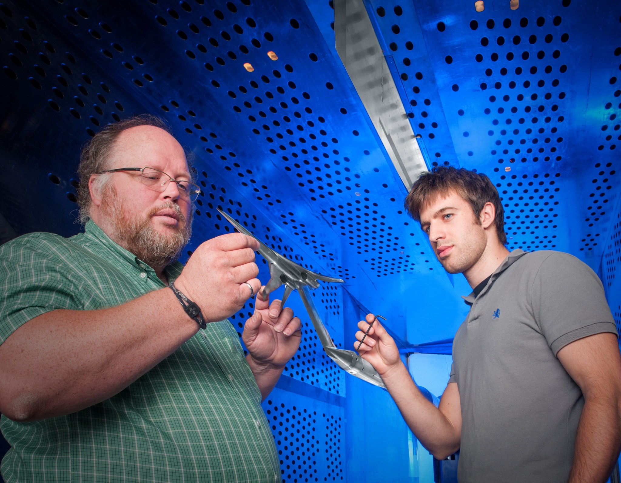 Two NASA technicians looking at a model in a wind tunnel.