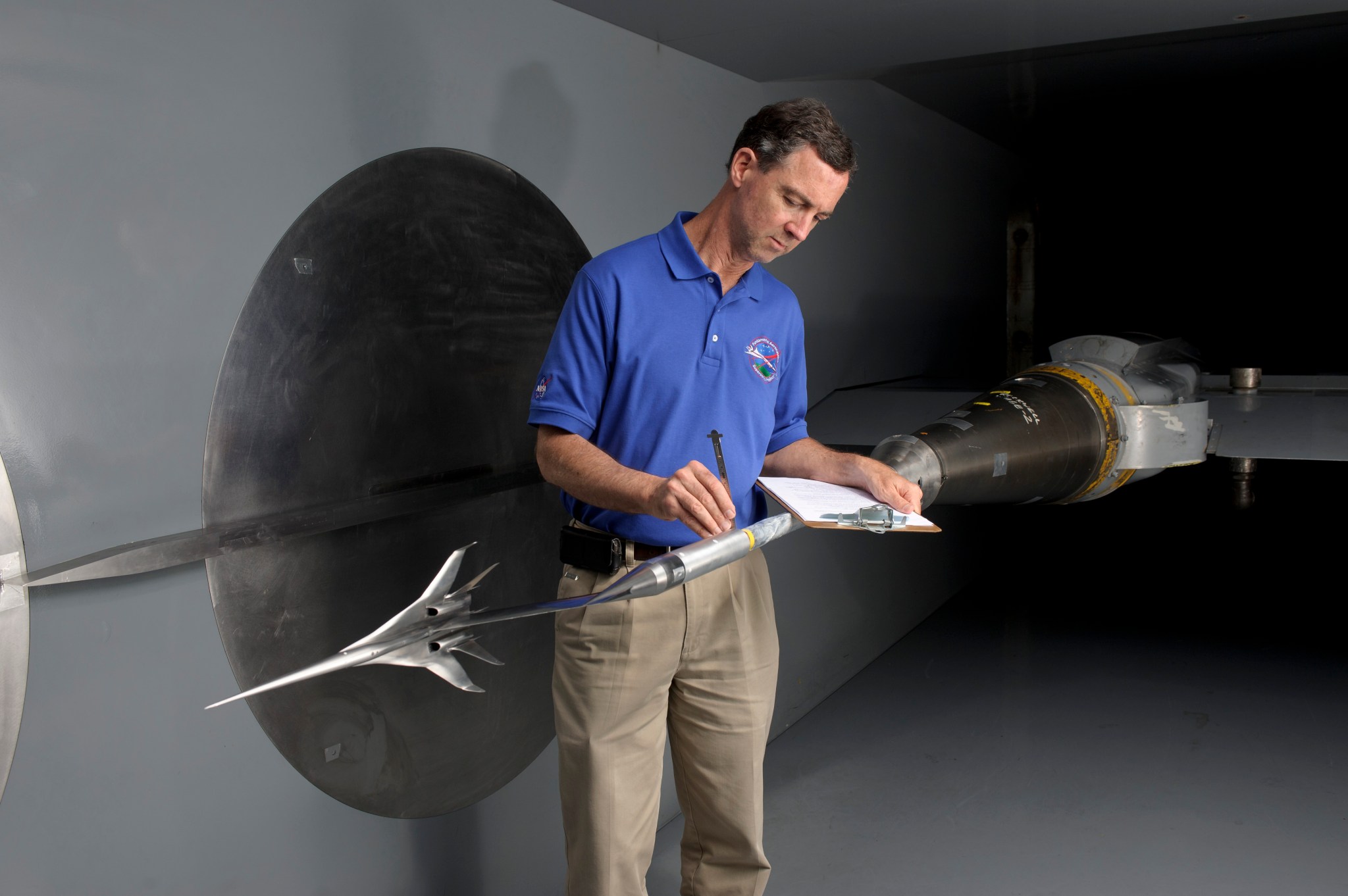 A man looking at 0.65% Scale Quiet Experimental Validation Concept (QEVC) Boom Model in wind tunnel.