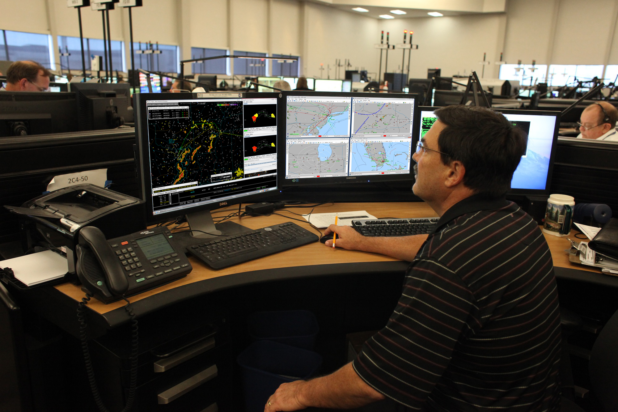 A man sitting at his desk with multiple monitors.