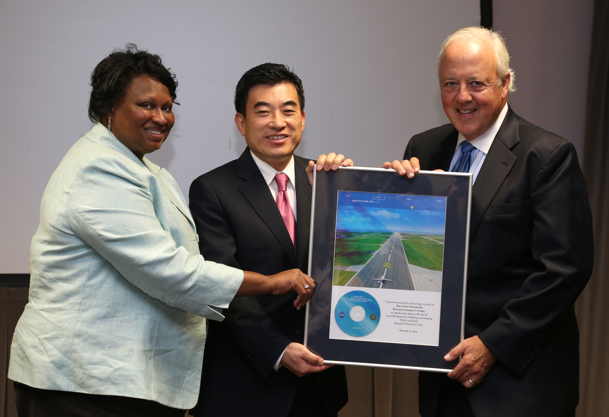 Dr. Shin handing over a framed image with a CD inside of the PDRC software to the FAA.