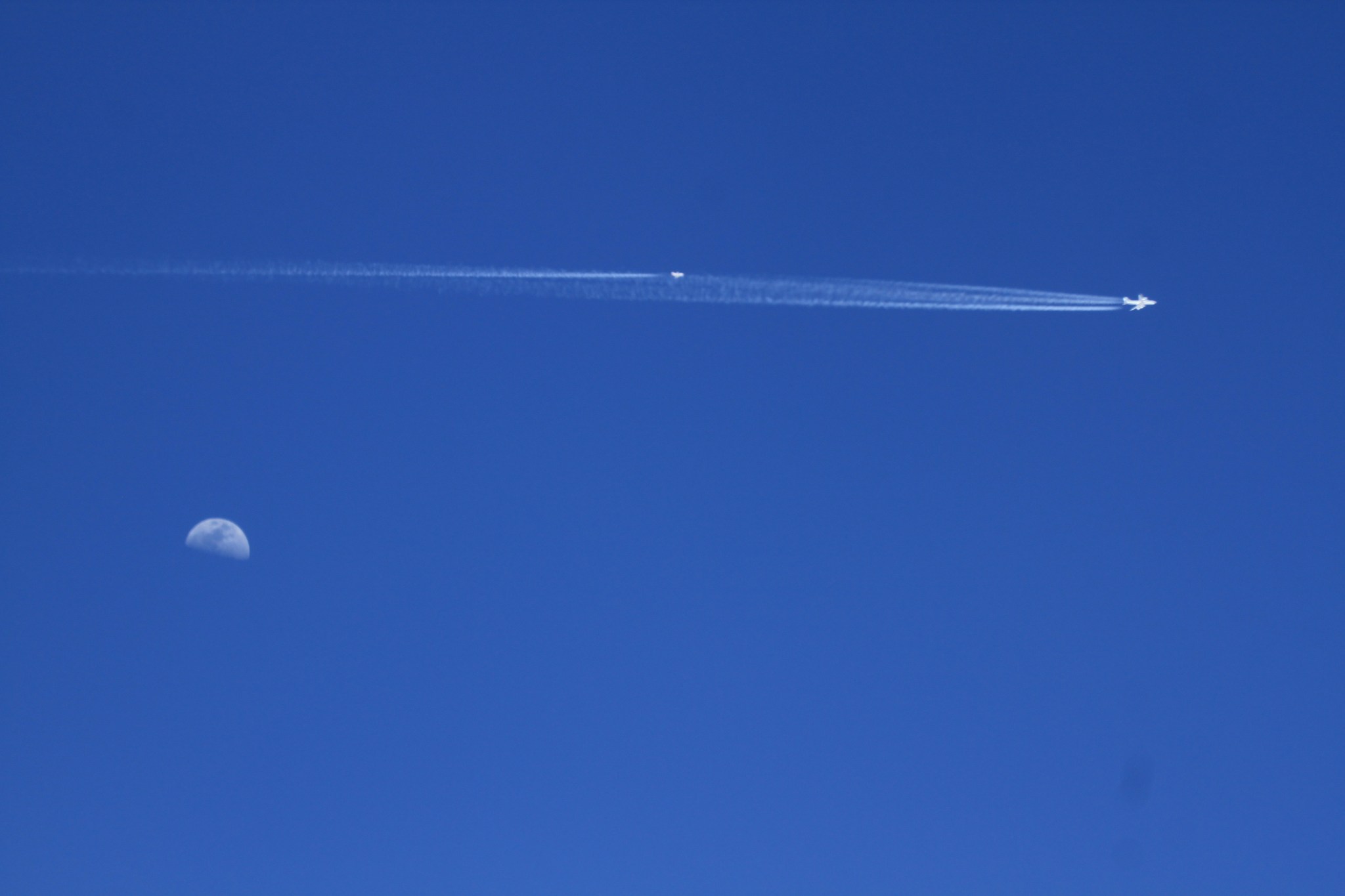 Planes over moon with contrails