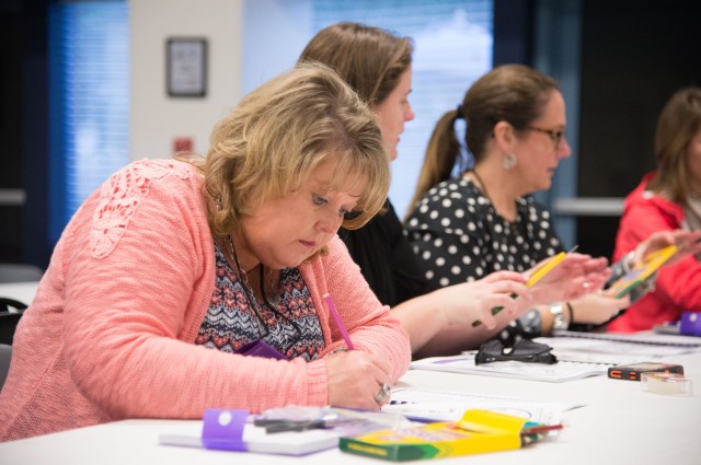 An educator takes notes as the staff of the Educator Resource Center at Space Center Houston provides information on how NASA