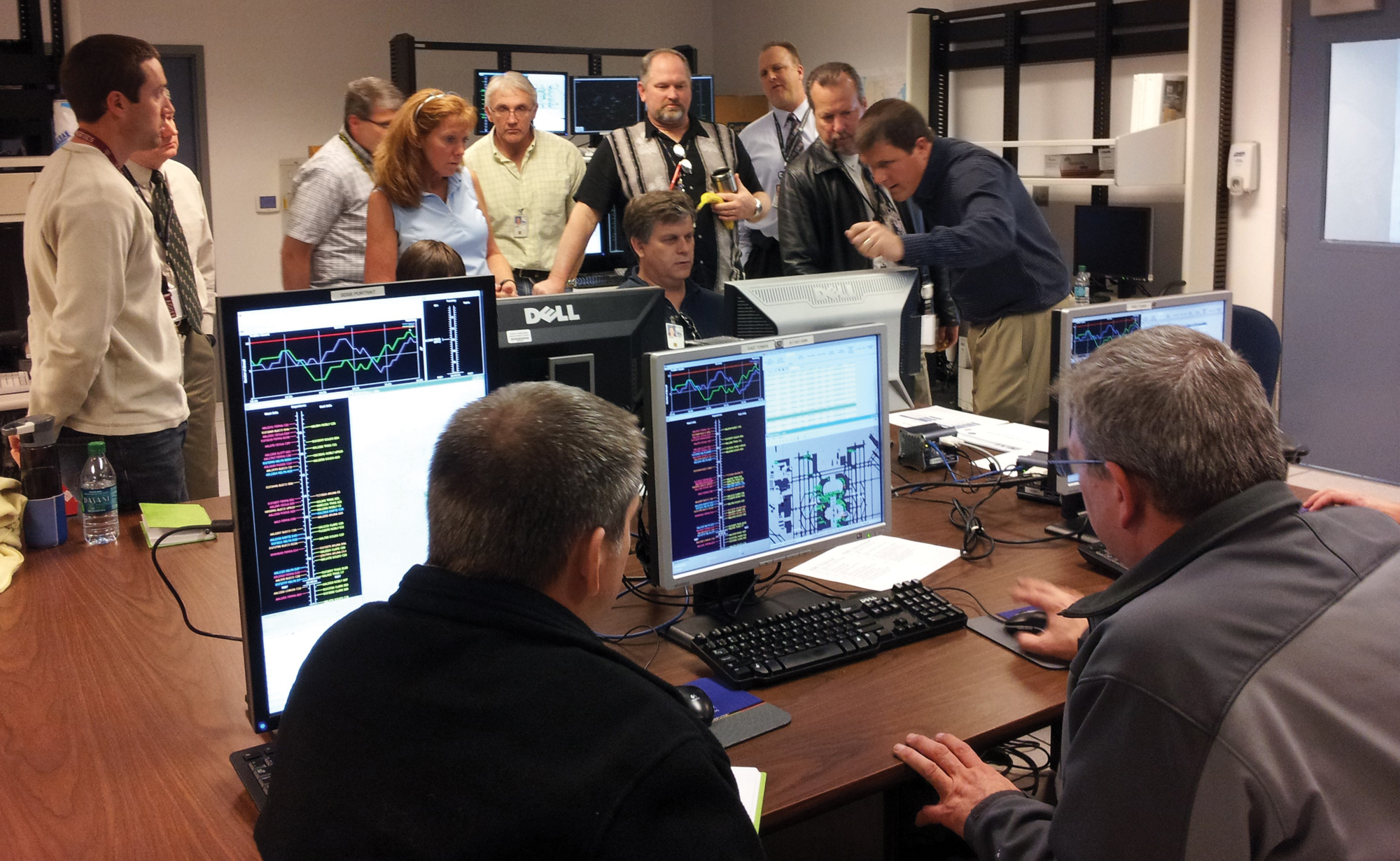 In a room, NASA and FAA traffic management coordinators gather around different monitors reviewing the PDRC system.