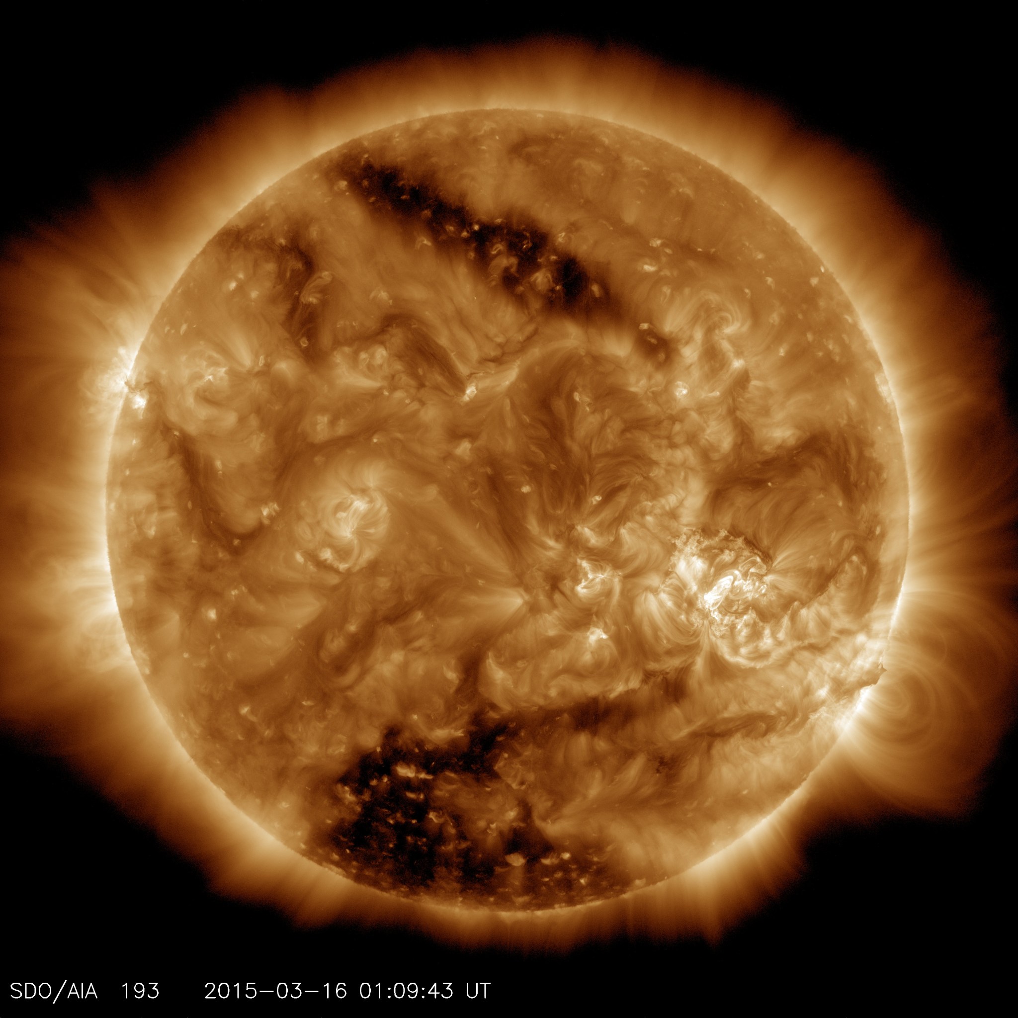 Two coronal hole, the two dark areas, on the Sun as seen by SDO. The Sun glows a pale orange with swirls of lighter yellow.
