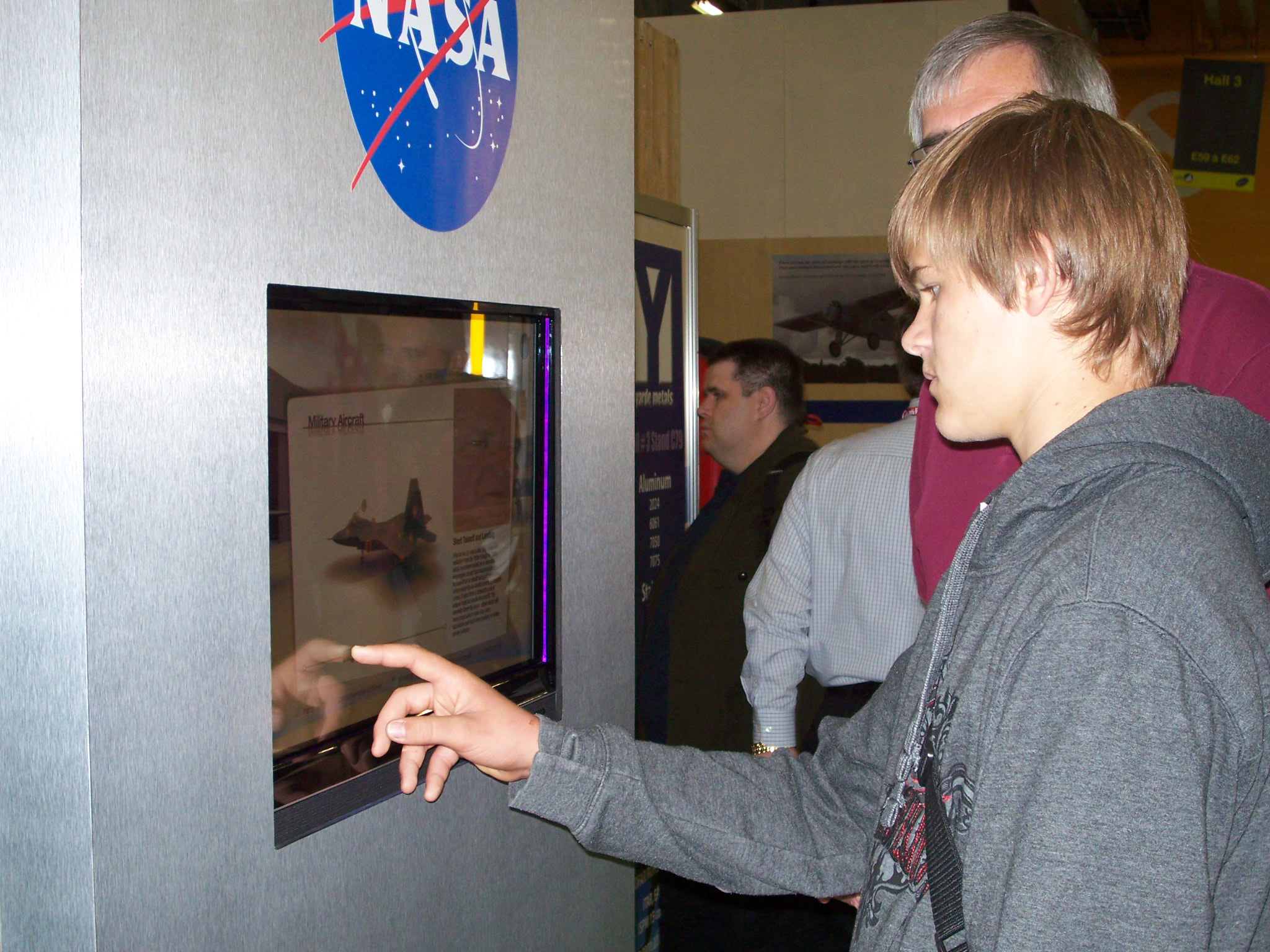 A young person using the touch-screen in the NASA exhibit booth.
