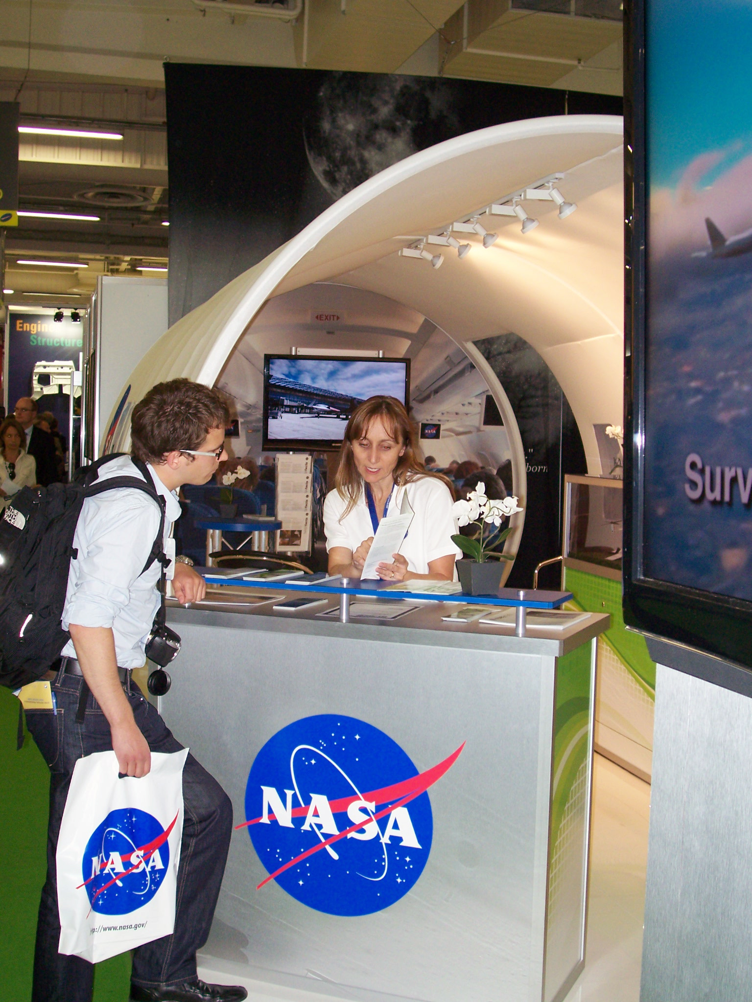 NASA personnel speaking with a member of the public at the NASA booth.