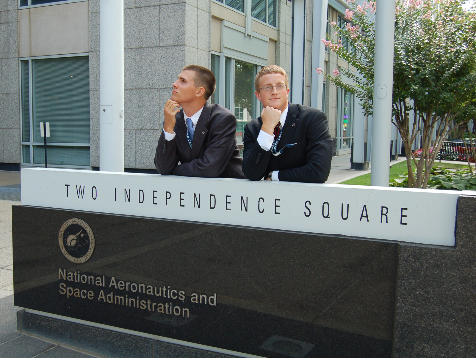 Two interns stading and posing in front of the NASA HQ sign.