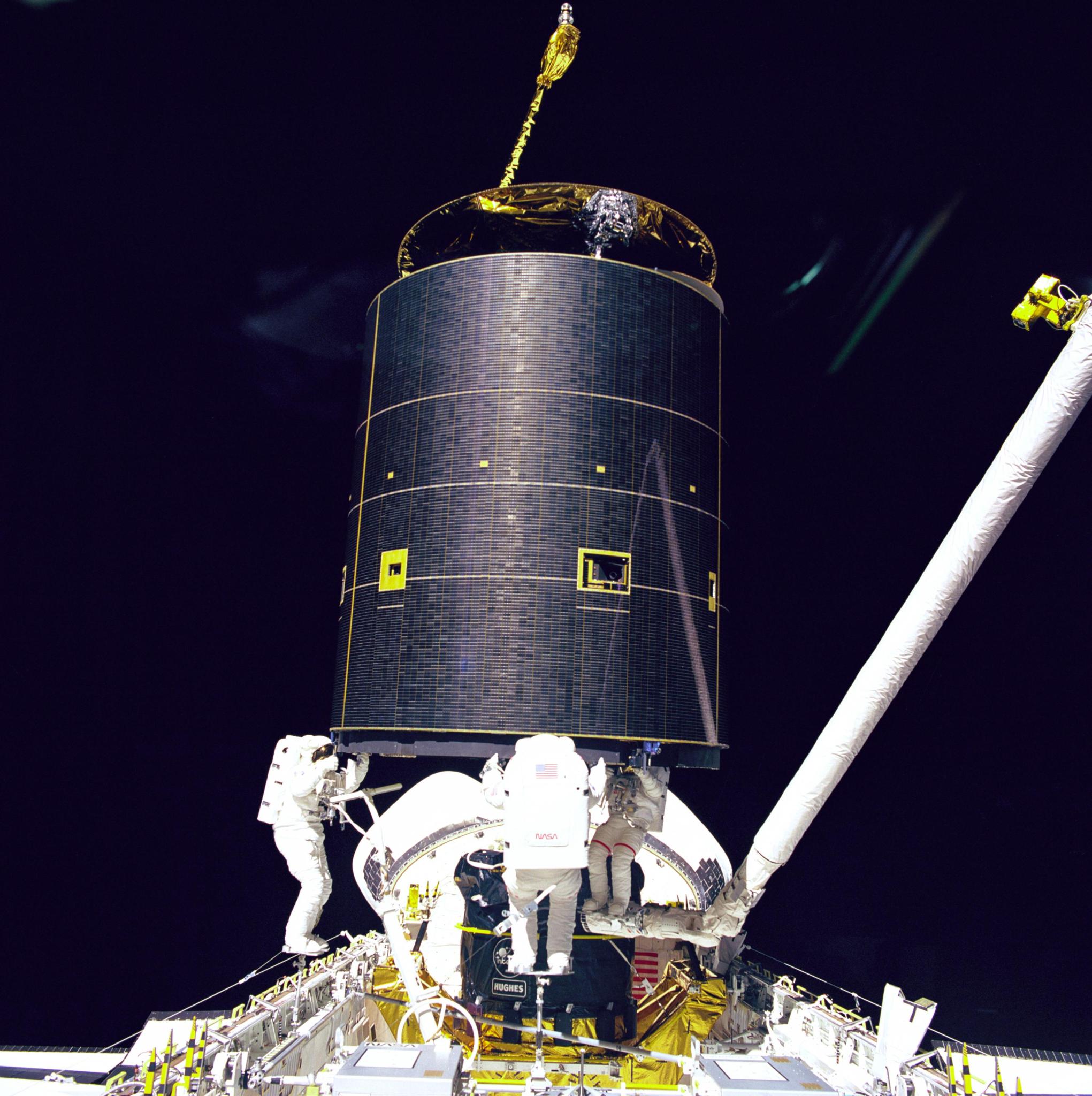 Spacewalking astronauts working on satellite
