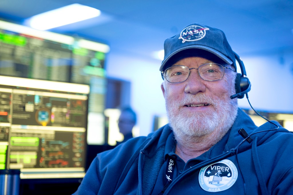 portrait of a man with glasses and a white beard, wearing a NASA baseball cap