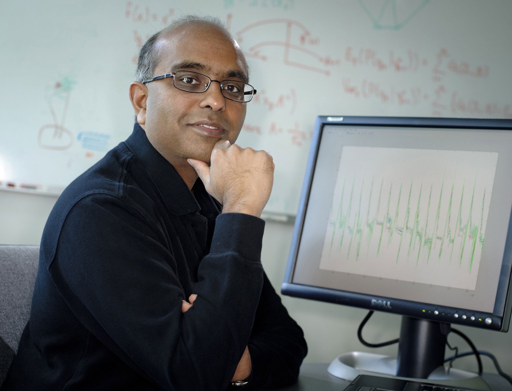 Ashok Srivastava sitting in front of a computer monitor.