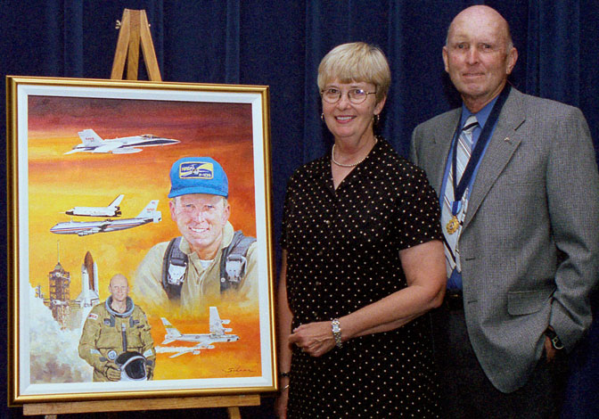 Gordon Fullerton and his wife Maria stand next to a framed painting honoring Gordon's career as a NASA astronaut and research pilot