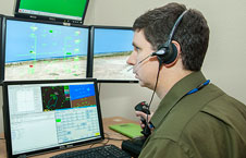 Man in headset looking at computer screens.